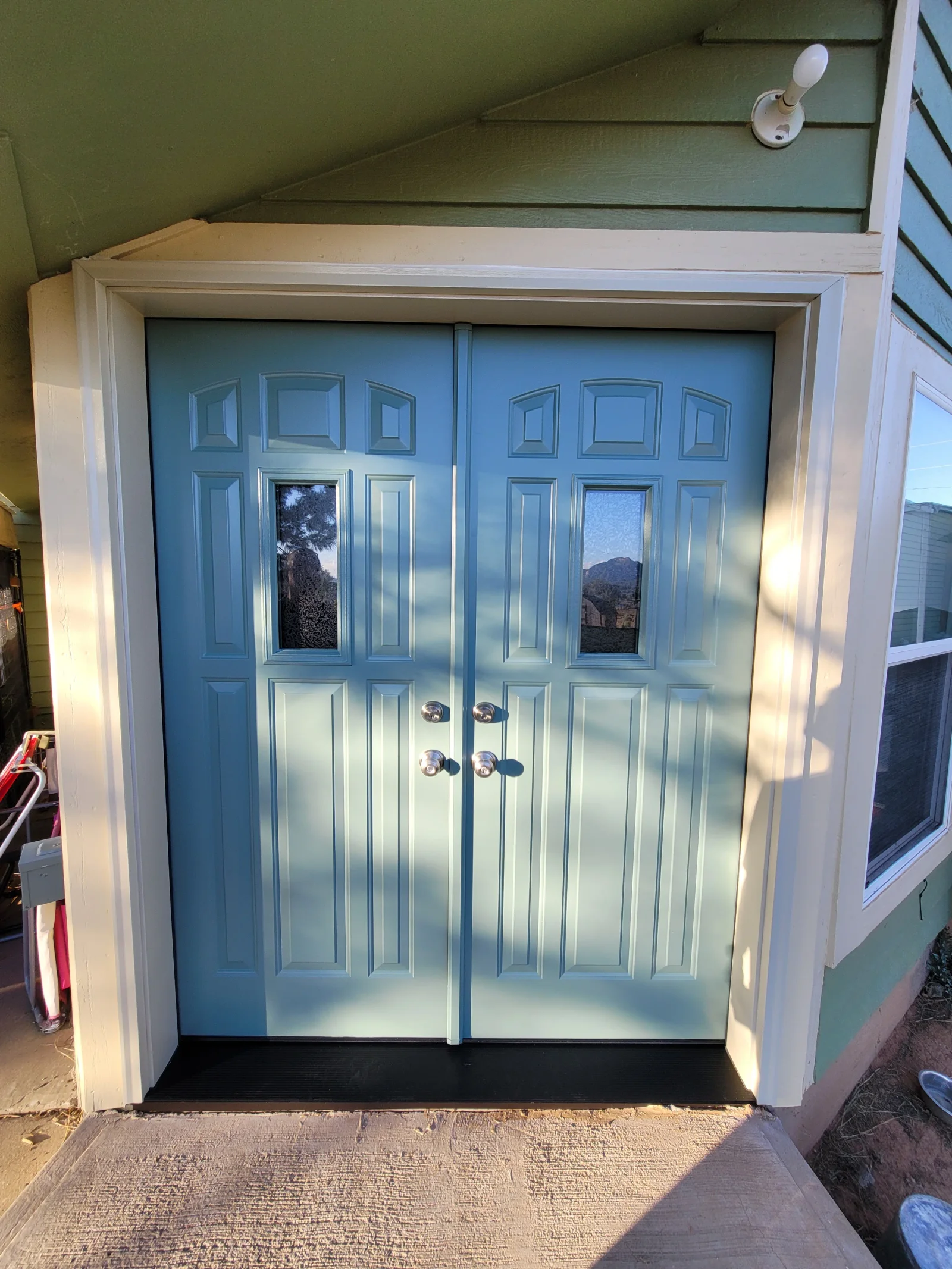 Blue steel double entry doors with raised panels, textured glass lites, and brushed nickel hardware in a cream trimmed frame